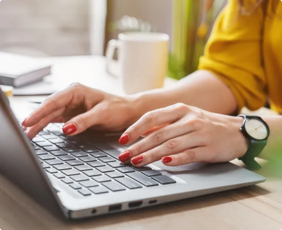 Mani femminili digitano sulla tastiera di un computer portatile